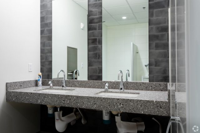 Bathroom sinks view of Atrium West with dark tiled walls and gray and white marble countertops